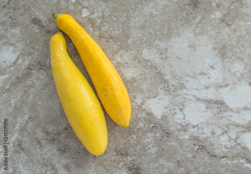 two ripe yellow summer squash on a gray marble countertop with copy space