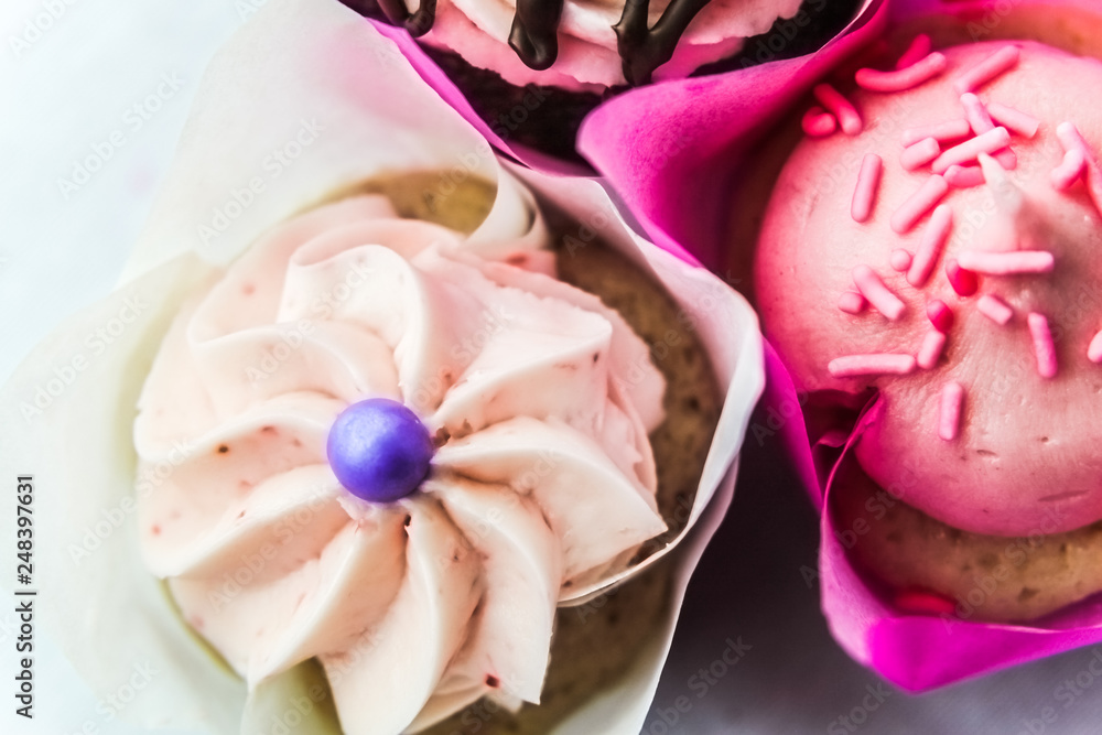 Three Cupcakes In Pink Wrappers Against A White Background Three Cupcakes In Pink Wrappers Against A White Background