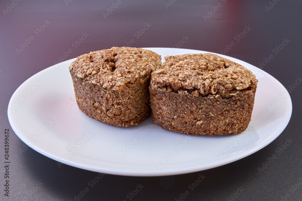 Vegan bread made at home with wheat germ and rye and buckwheat on a white plate on a black background. healthy food. natural products