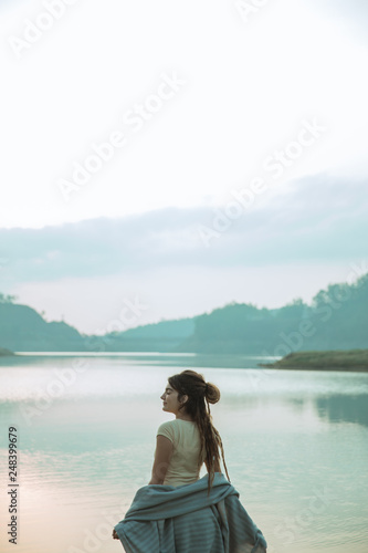 portrait caucasian women standing with blanket enjoy and relax side the river in the morning, back view