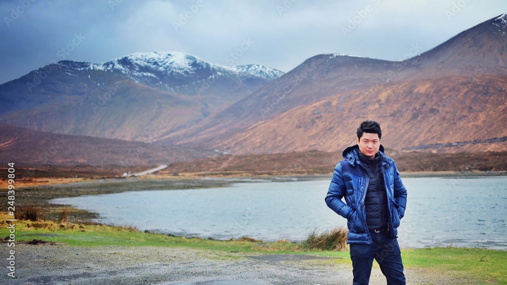 Asian man with beautiful view of  mountains and river in Highland,Scotland, United kingdom