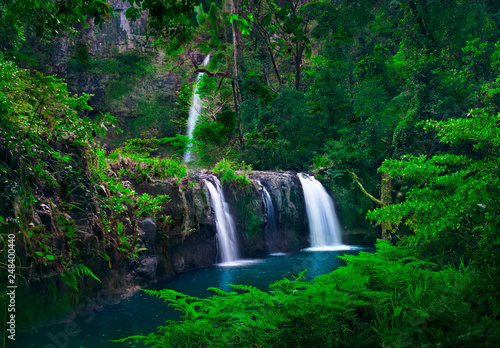 Beautiful scenery of cascade of tree waterfalls tumbling down the moss-covered cliffs by the mountainside with plants.Nandroya Falls Atherton Tablelands. Far North Queensland. Australia.-Image.  photo