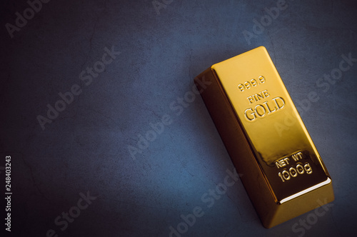 Photos An ingot of gold metal bullion of pure brilliant diagonally located on a blue textured background