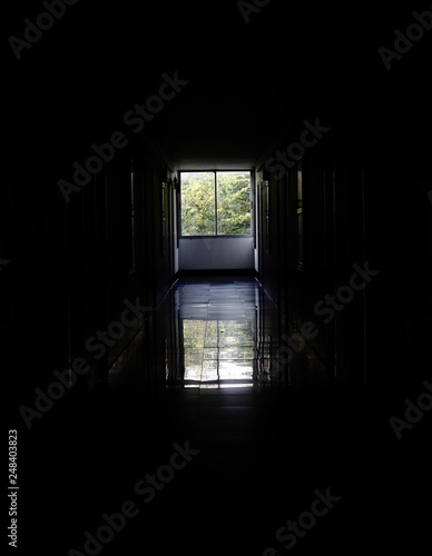 Long corridor or tunnel in haunted and ruined abandoned industrial building. Light in the end of tunnel. Way to freedom concept