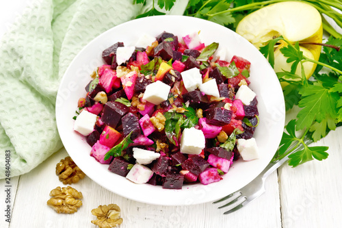 Salad with beetroot and walnuts in plate on board