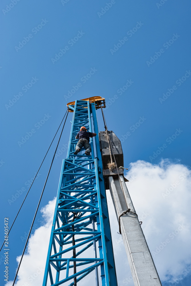 Worker wear orange helmet climb very high crane in hot day for pile. Worker wear orange helmet climb very high crane in hot day for pile.