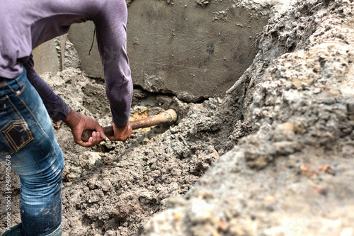 A worker is digging a hole by using hoe / house construction