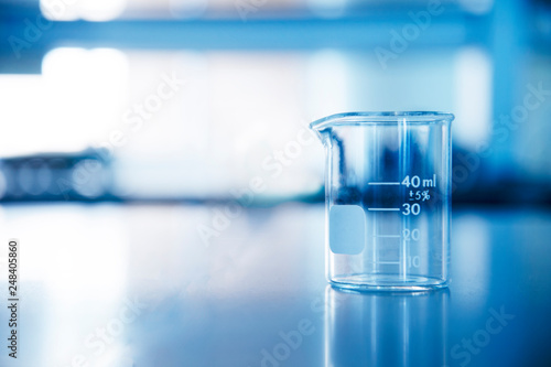 single glass beaker in chemical science laboratory for research and education in blue background
