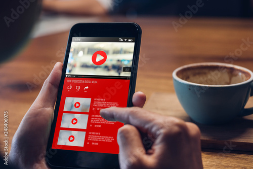 Fotografia close up woman hand holding mobile watching video online with advertising on mobile on sofa at home
