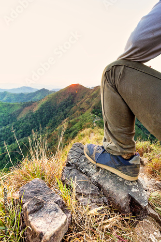 Hikers lay down resting and show feet with wearing shoe at top of mountain.