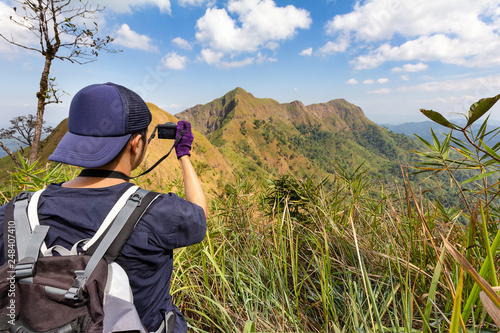 Young hiker taking a photography along path of terkking. Photographer taking photo at mountain peak. photo