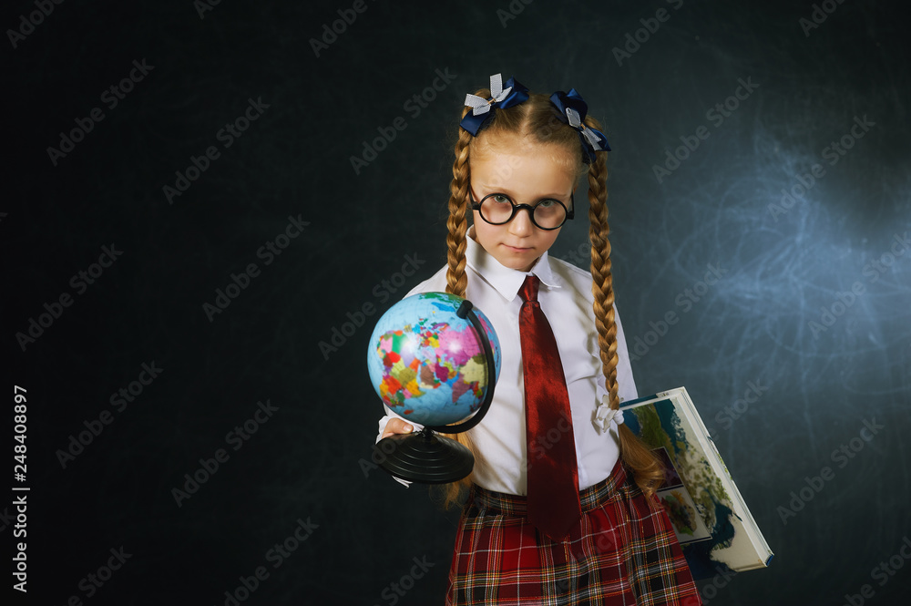 Fototapeta premium Portrait of a girl primary school student on a dark background