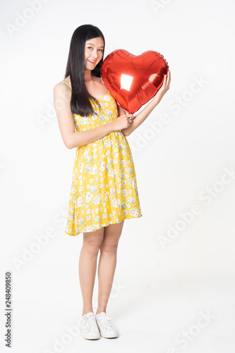 Asian young woman in yellow dress hold  red balloon heart. Young woman holding it with  being excited and surprised  holiday present isolated white  background.concept love surprise valentine day. © anon