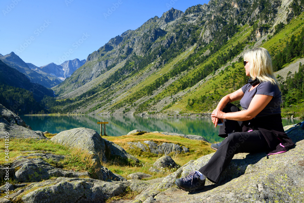 Tourist sitting on rock at Gaube lake. Hautes Pyrenees, France.