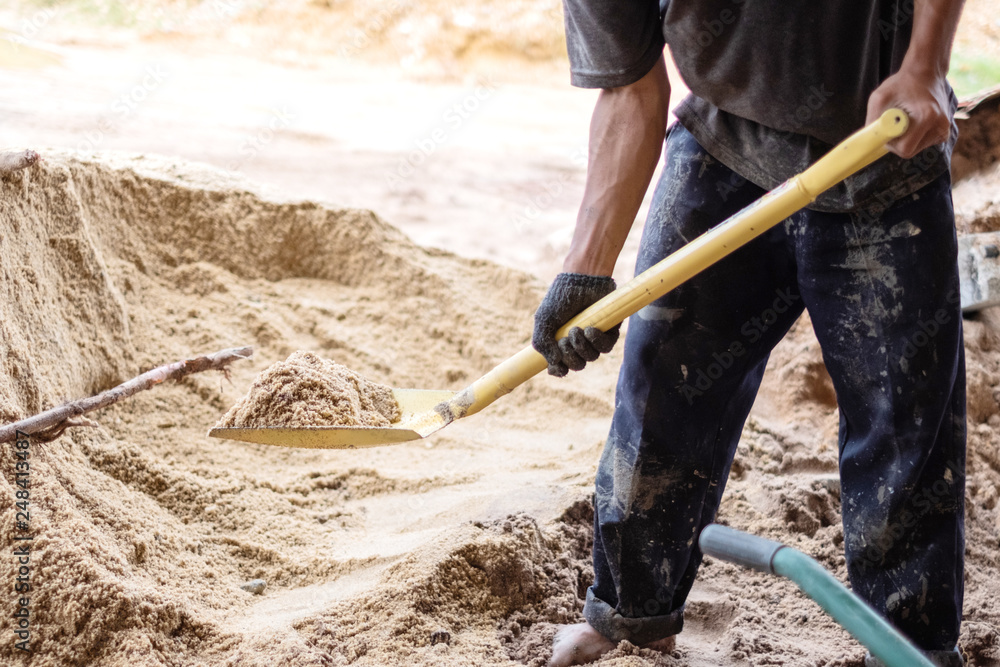 A worker use the shovel to fill the sand into the wheelborrow for  construction of new house. Construction tools. Stock Photo | Adobe Stock