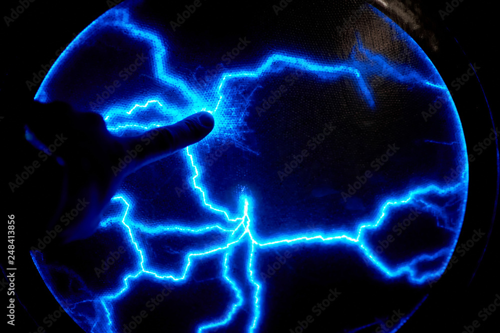 Finger touch electric plasma ball on a dark background. Static electricity model Finger touch electric plasma ball on a dark background. Static electricity model