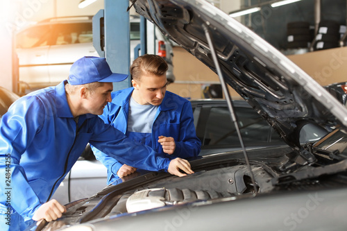 Male mechanics fixing car i...