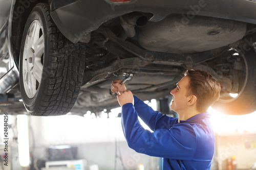 Male mechanic fixing car in...