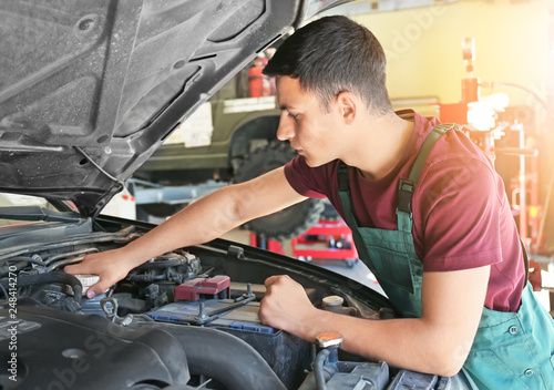 Young auto mechanic repairing car in service center