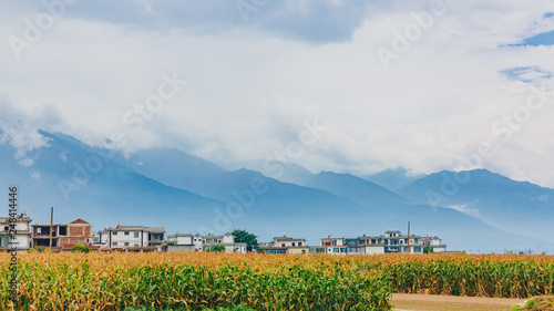 Houses and fields under Cangshan Mountains covered in clouds, in Dali, Yunnan, China