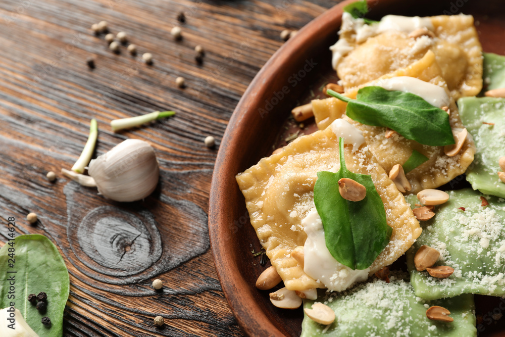 Plate with tasty ravioli on wooden table
