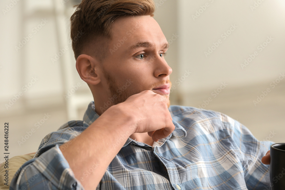 Handsome young man drinking coffee at home
