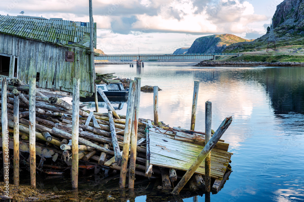 Fototapeta premium Ruined wooden house on the shore of a beautiful sea in a mountain landscape