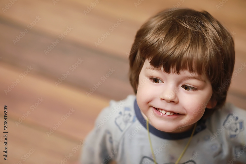 Portrait of a small curly-haired boy. A child wrapped in a rug eats an apple. A two-year-old boy hides under a blanket. Portrait of a small curly-haired boy. A child wrapped in a rug eats an apple. A two-year-old boy hides under a blanket.