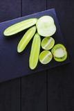 Green fruits, vegetables on a black background with copy space. Creative figure of natural green products. Cucumbers, kiwi, lime and green apple on a slate board