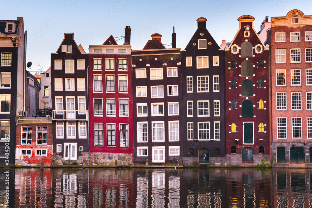 Front view of beautiful colorful traditional Amsterdam houses on the Amstel river bank reflecting in the river. Traditional dutch architecture