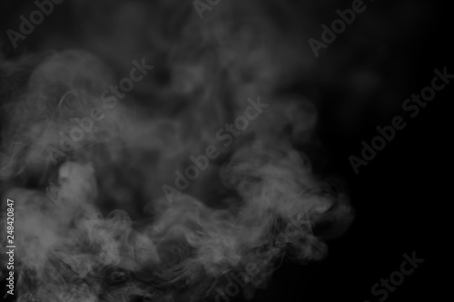 White smoke on a black background. Texture of smoke. Clubs of white smoke on a dark background for an overlay