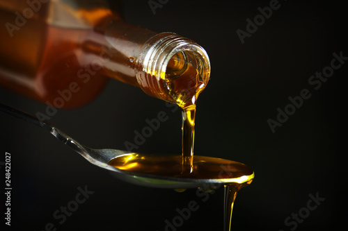 Oil pouring to the spoon from the bottle