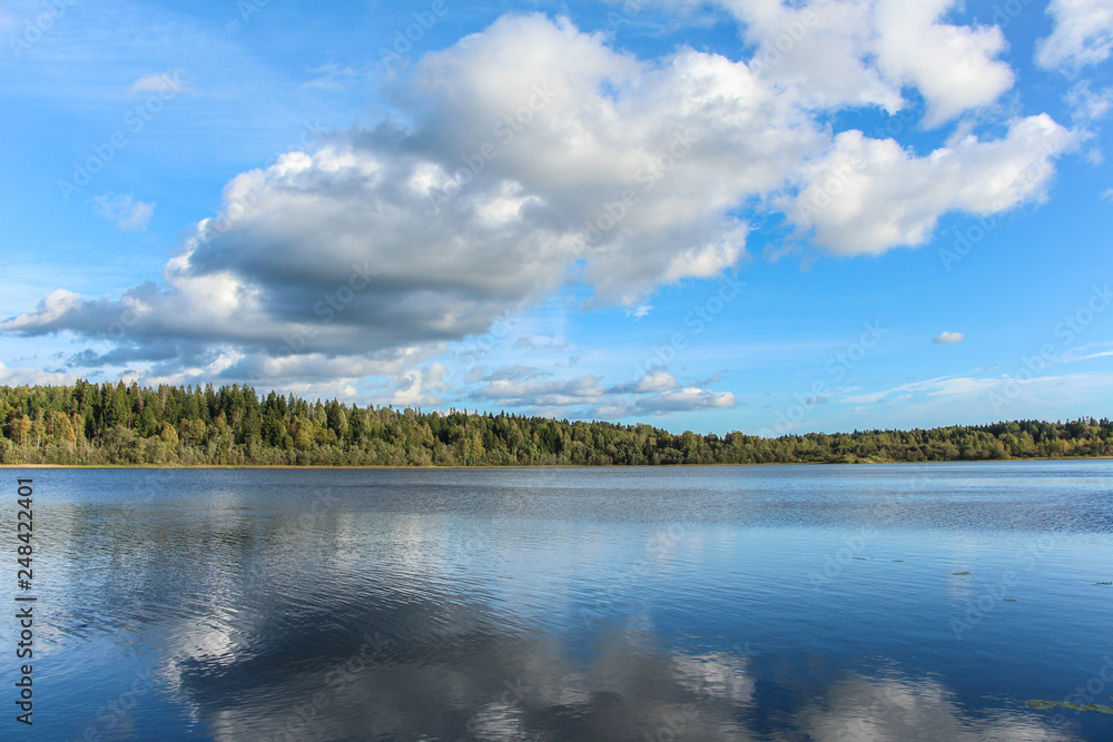 Clouds are reflected in the smooth surface of the lake on a sunny day. Valdai, Russia.