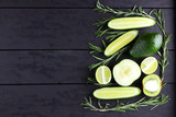 Green fruits, vegetables and rosemary on black boards with a copy space. Avocado, lime, kiwi and green apple on wooden boards. Cucumbers and rosemary branches top view. Healthy food