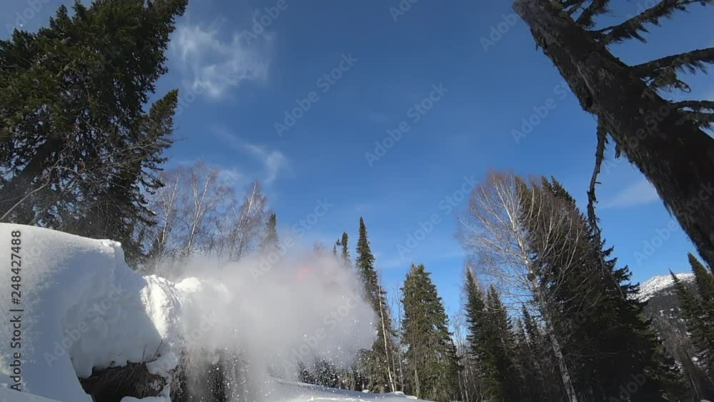 jump over the hill on a snowmobile. the guy on the bright snowmobile. riding in the woods with a jump. blue sky, old mountain forest. with splashes of snow and whirlwinds. side and back view. Slowmo jump over the hill on a snowmobile. the guy on the bright snowmobile. riding in the woods with a jump. blue sky, old mountain forest. with splashes of snow and whirlwinds. side and back view. Slowmo