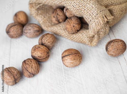 walnuts in a bag on a white wooden background