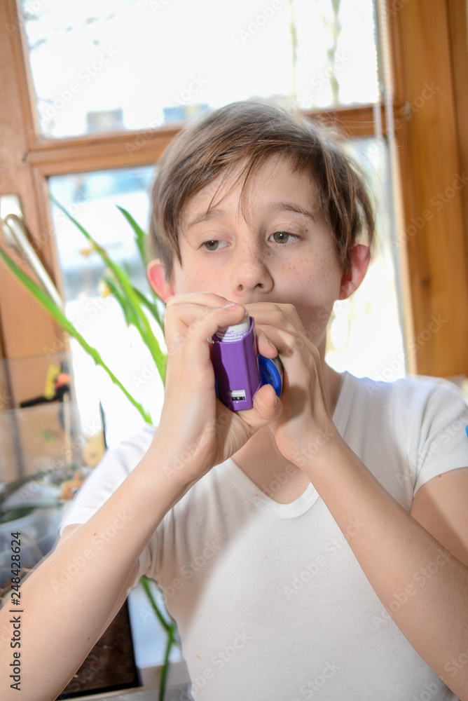 Boy with asthma uses an inhalator to prevent an attack Boy with asthma uses an inhalator to prevent an attack