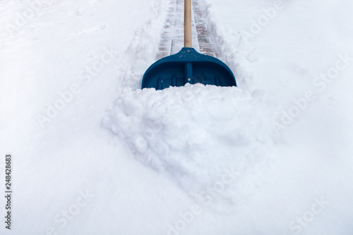 Cleaning snow with shovel in winter day