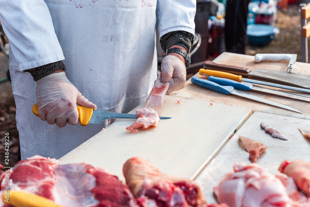 a butcher with a knife separates fat from bacon