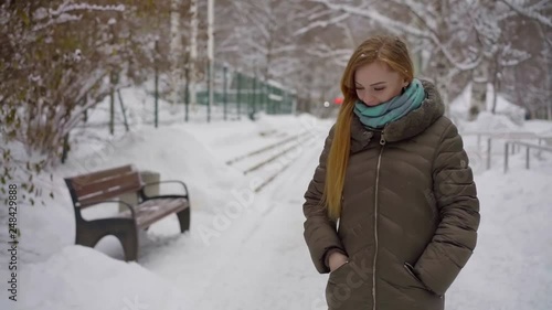 Charming blonde girl peacefully walking in a city park in in beautiful wintetime. photo