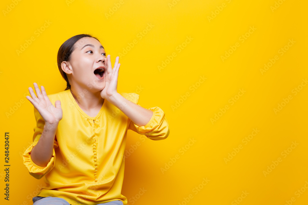 Happy woman making shout gesture isolated over yellow background Happy woman making shout gesture isolated over yellow background