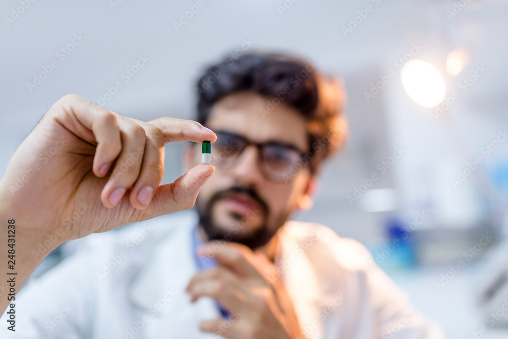 Young attractive male scientist holding a pill Young attractive male scientist holding a pill