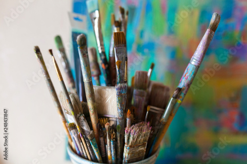 A close-up of the artist's used brushes in a glass