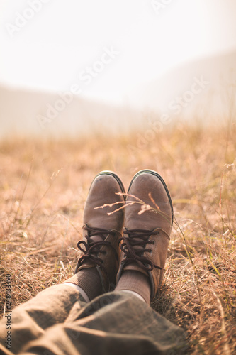 Legs in Brown shoes on brown grass at mountain