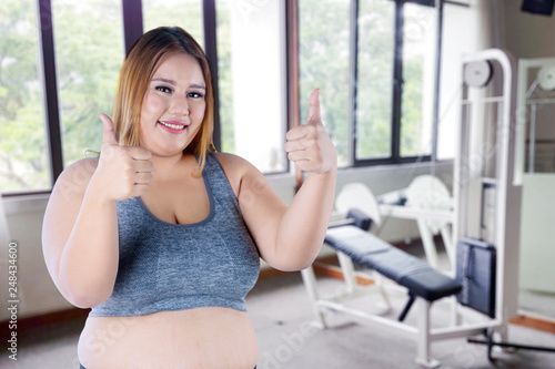 Pretty fat girl showing thumbs up in gym center Free Download Pretty fat girl showing thumbs up in gym center - GFXLoad