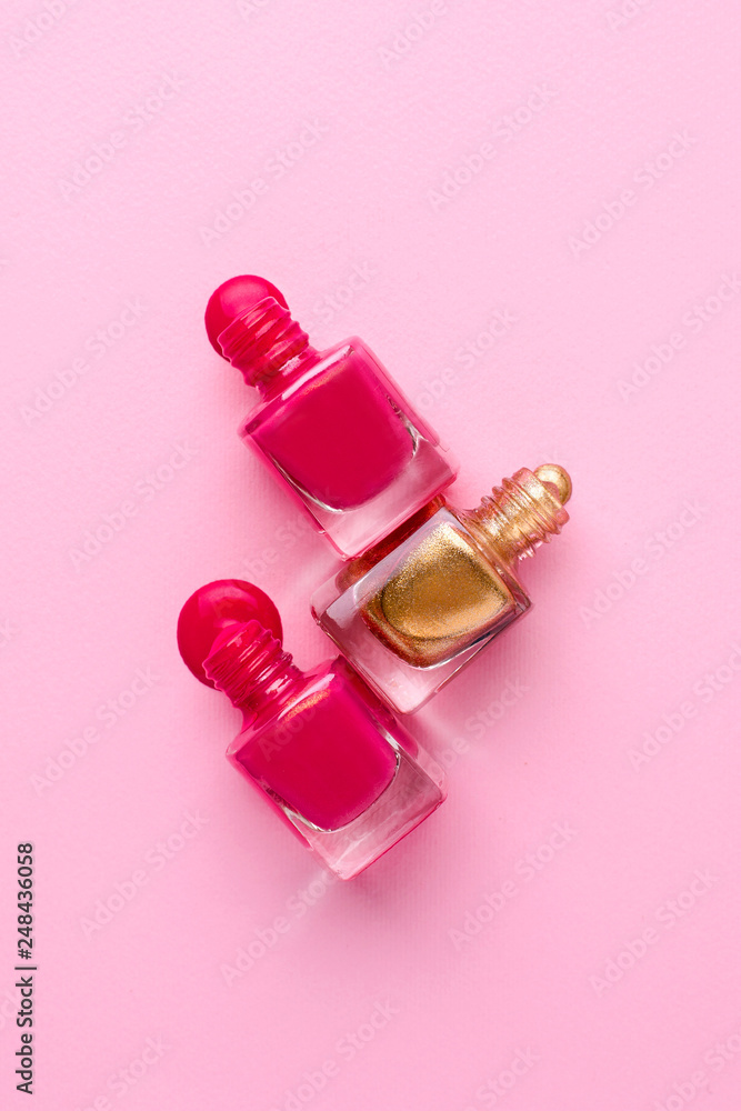 Cosmetic pink and gold nail polishes on a pink background Cosmetic pink and gold nail polishes on a pink background