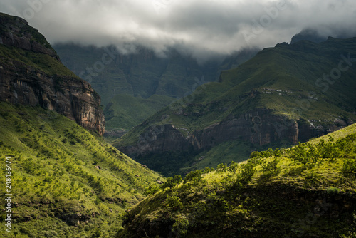 Dramatic afternoon light falls on the hills along the Tugela Gorge hiking route at the base of the Amphitheatre mountain. Drakensberg, South Africa