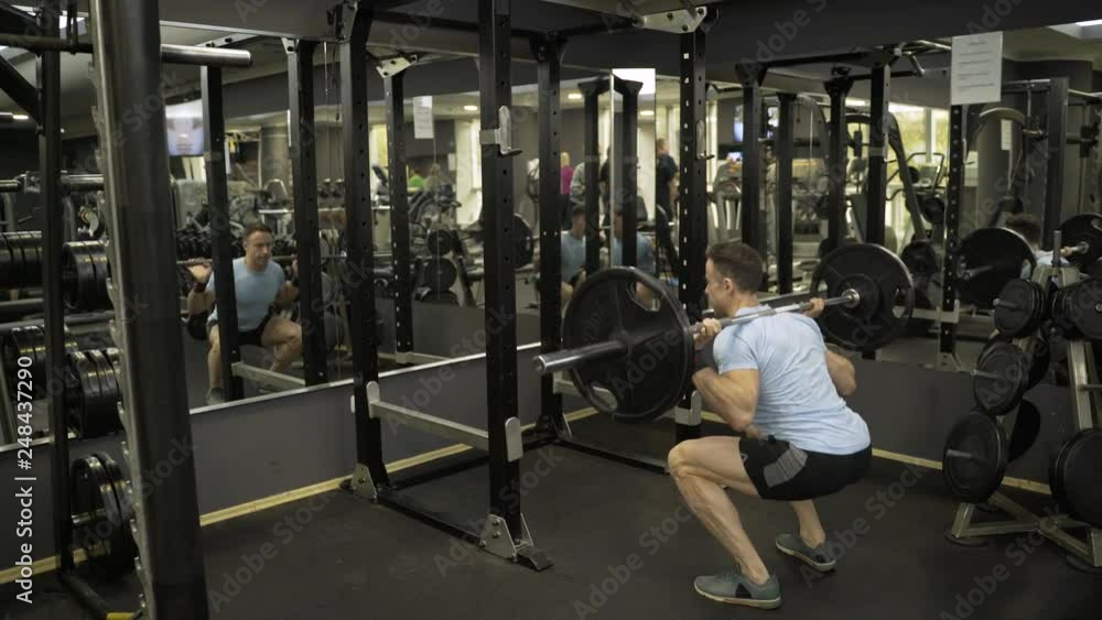 Attractive man holding barbell behind neck at the gym. Attractive man holding barbell behind neck at the gym.
