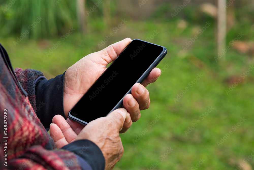 Close-up of hand man holding smartphone in his garden.