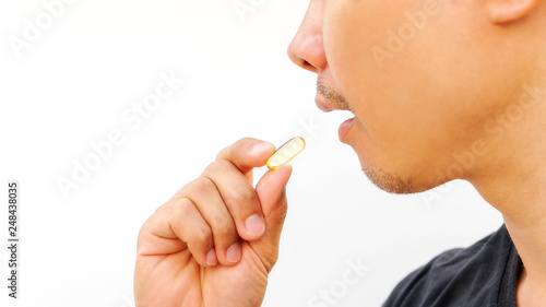 Man taking a supplement pill on a white background.